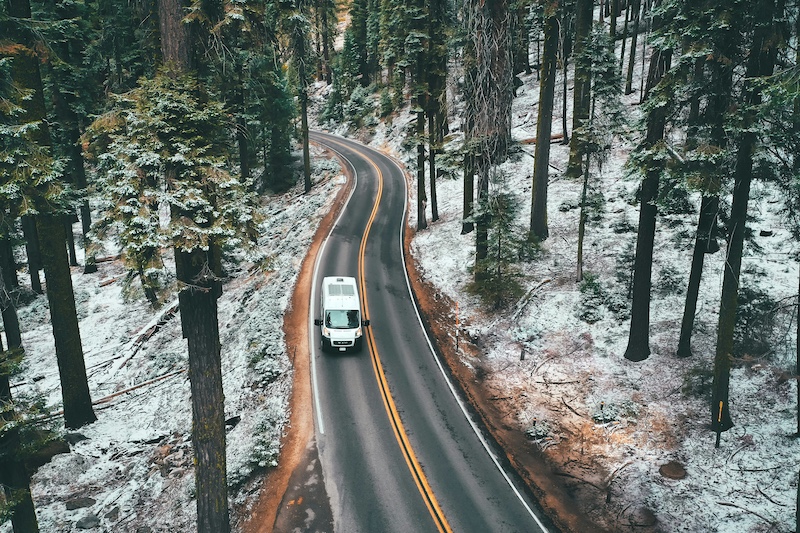 A camper van driving on a forest road in the winter